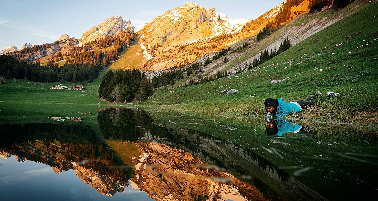 Girl drinking out of lake threw straw.